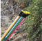 Multicolored fiberoptic cables being installed in a trench next to dirt and green plants