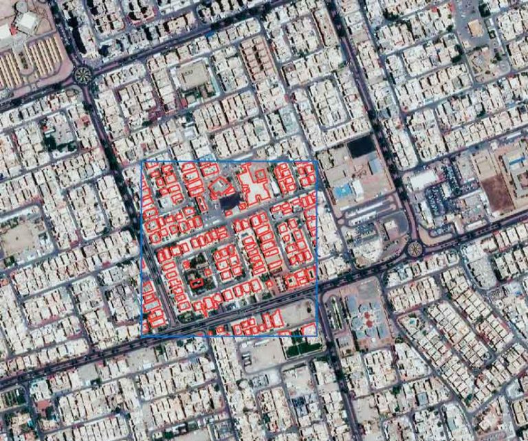 Satellite imagery of a neighborhood in Kuwait city with one area surrounded by a square blue line and the buildings within that square outlined with red lines