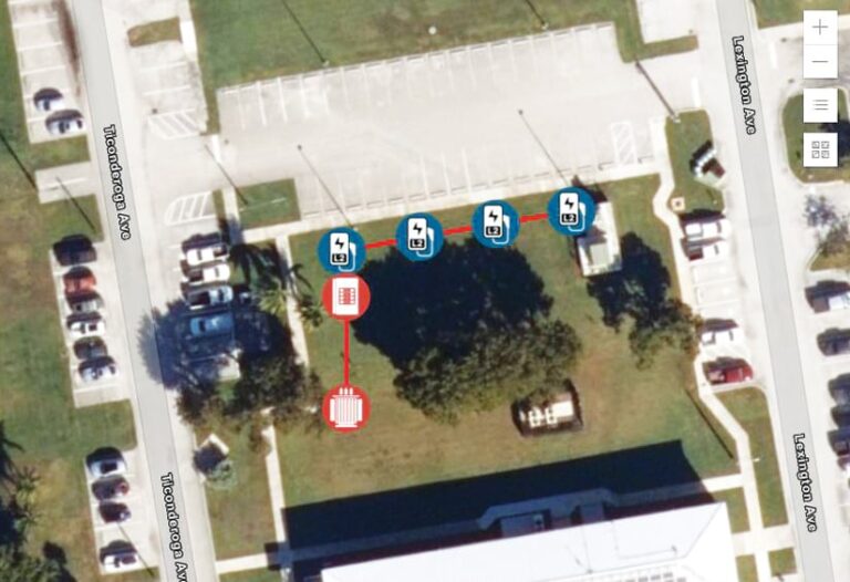 Viewed from overhead, several connected parking areas, two streets, and a building surround a grassy area with a few trees along with six blue or red circles with symbols, all connected by a red line.