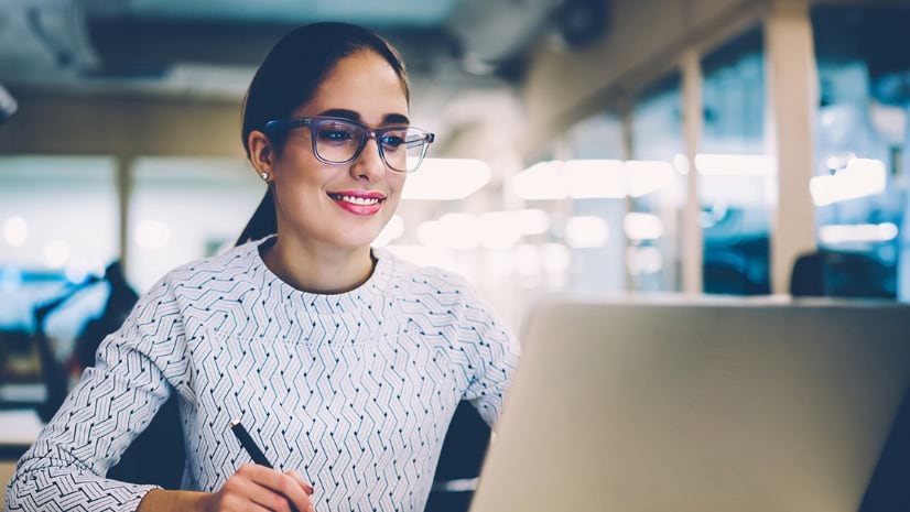 A person smiles at a laptop.