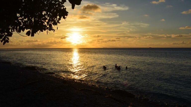 Young people gather for a swim as the sun sets.