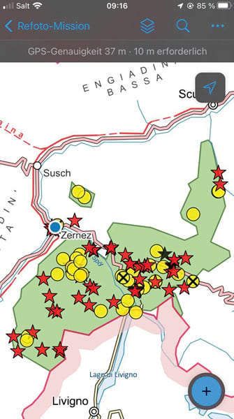 A mobile app screen that shows a map with several trails on it and an area highlighted in green that has points of interest marked with red stars and yellow circles, plus a blue dot indicating where the user is