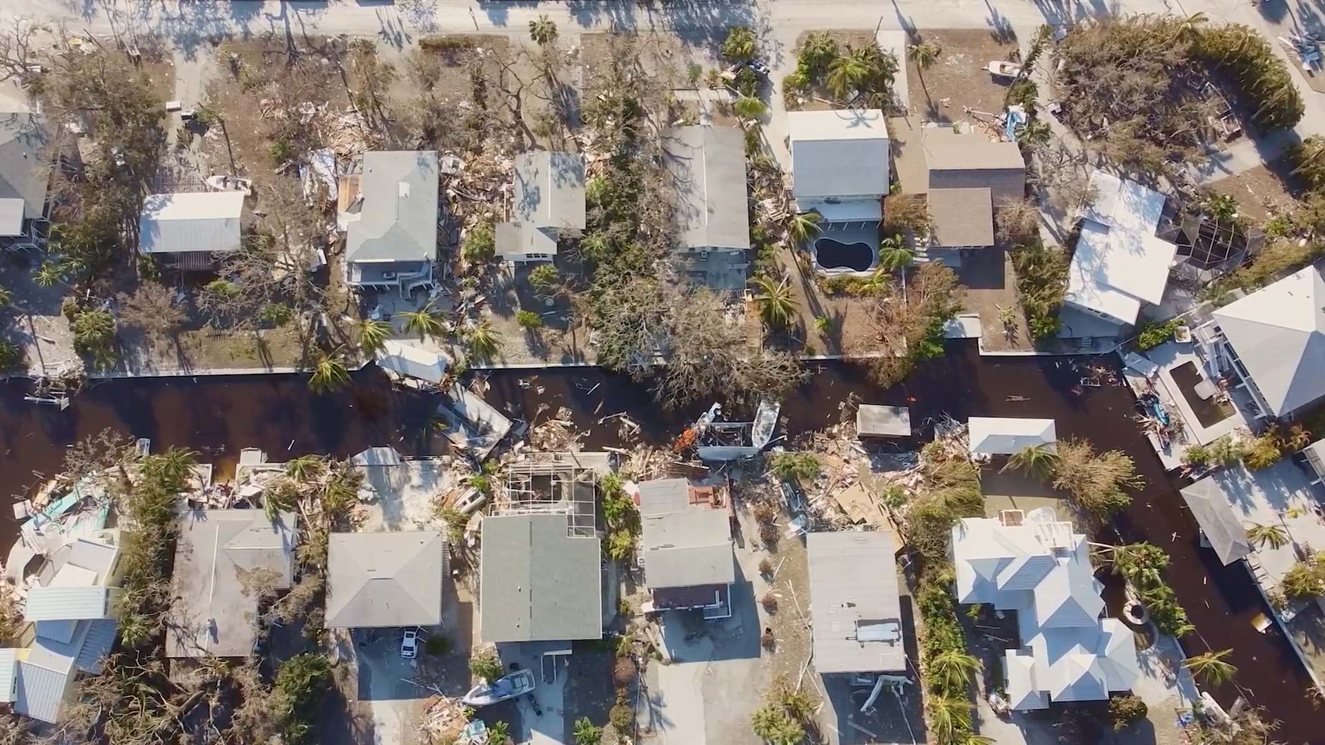 An aerial view of hurricane damage in a residential neighborhood bisected by a canal