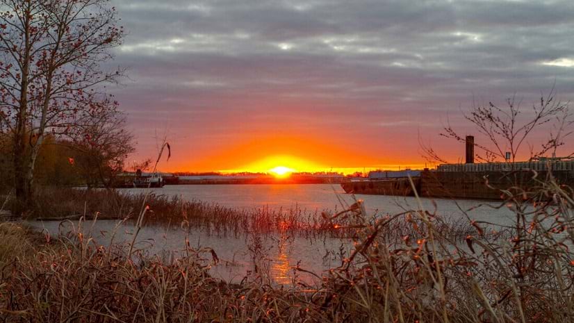 The sun sets behind a body of water.