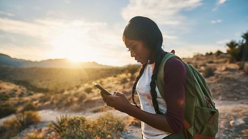 A person stands outside gazing at a mobile device