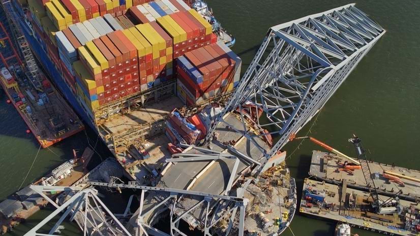 A shipping vessel and damaged bridge are seen from above