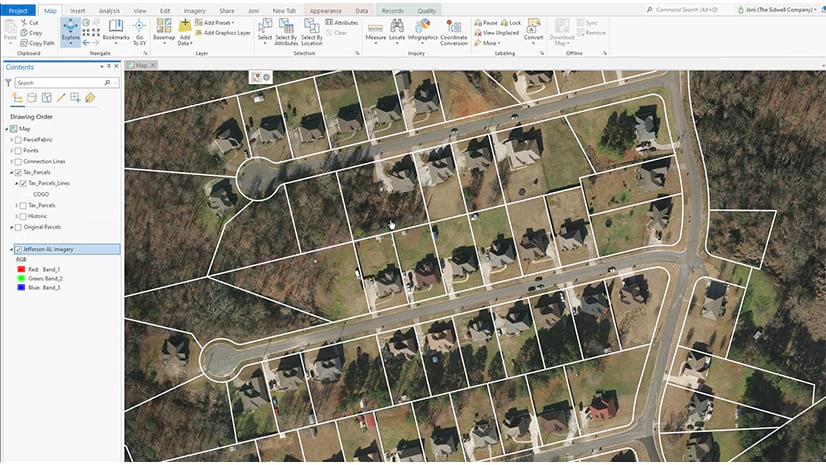 An aerial view of a suburban neighborhood with property lines overlaid on the image. The property lines do match the property boundaries shown in the aerial view. A GIS software menu is visible on the left and top of the screen.