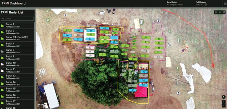 Aerial view of an archaeological dig site. The site is divided into numbered rectangular plots that are blue, green, or gray. Some sections of rectangles are outlined in yellow, others in pink.