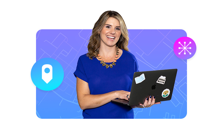 سيدة مبتسمة ترتدي بلوزة بلون أزرق ملكي وتحمل جهاز كمبيوتر محمولًا مفتوحًا