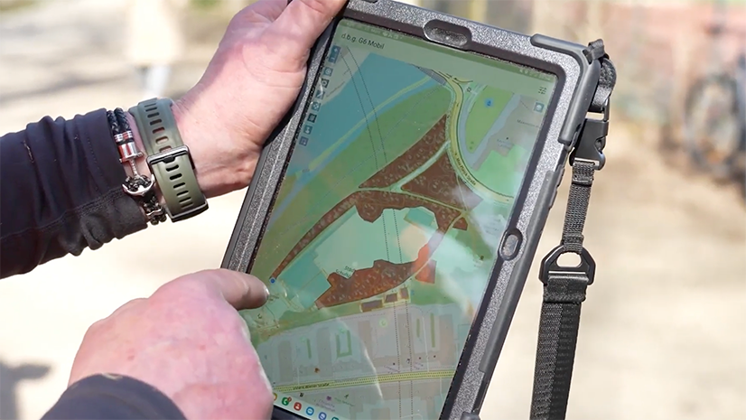 A mobile worker uses a tablet to view a map of a proposed construction site for an underground railway. The map shows the location of underground infrastructure and other important features to plan the next phase of construction.