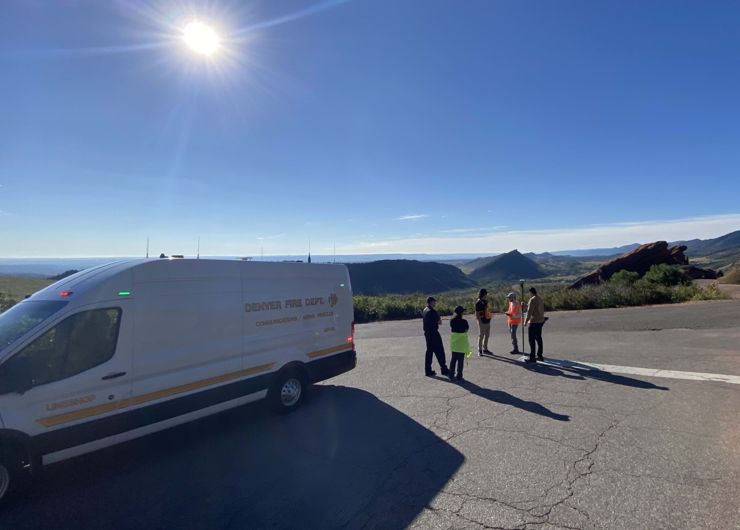 A team of people stand by a van overlooking the mountains