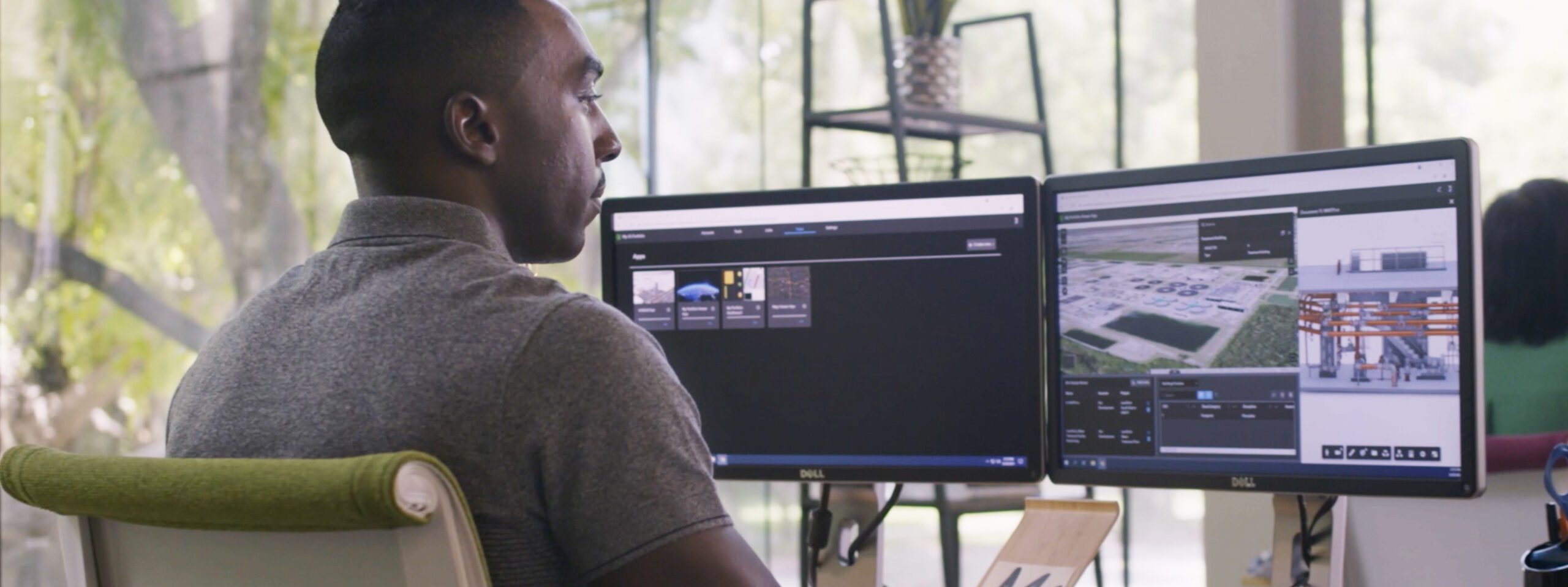 A person working in an office on dual monitors showing a project in ArcGIS GeoBIM.