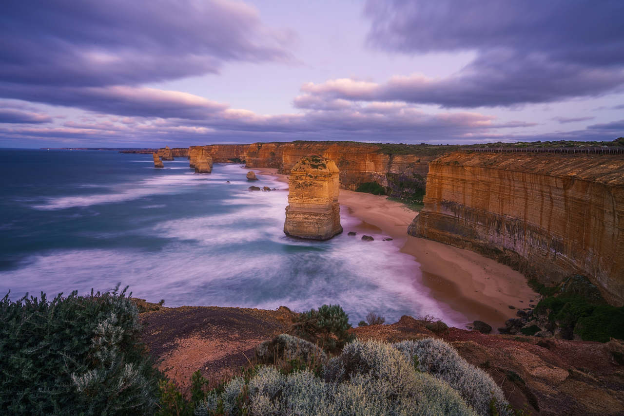 Purple sunsets over a beach by a cliff in Australia