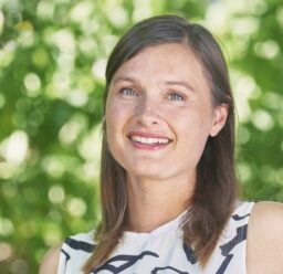 A head shot of Virginia Zaunbrecher in front of a leafy green background.