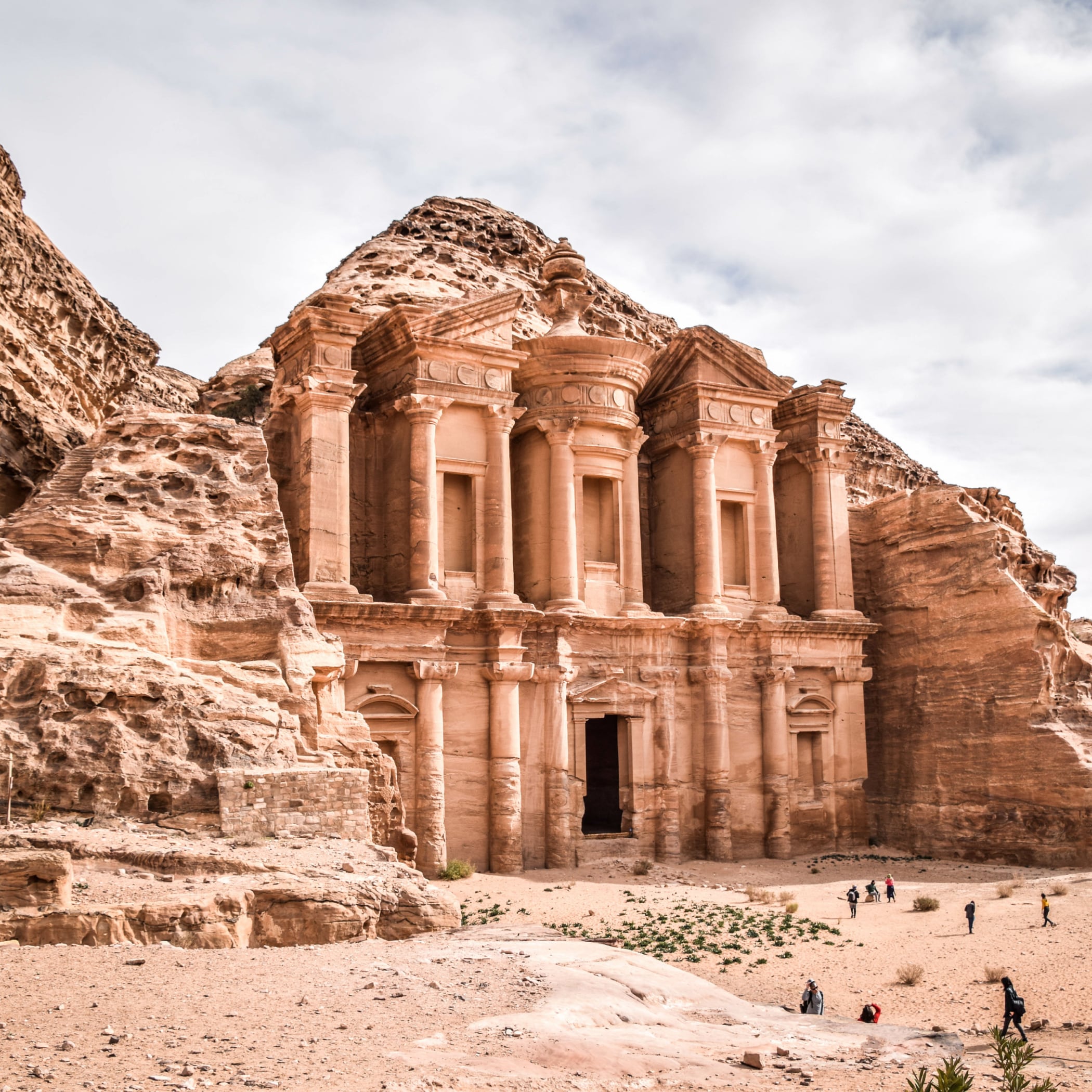 A rock-cut tomb carved directly into a sandstone hillside in a desert landscape