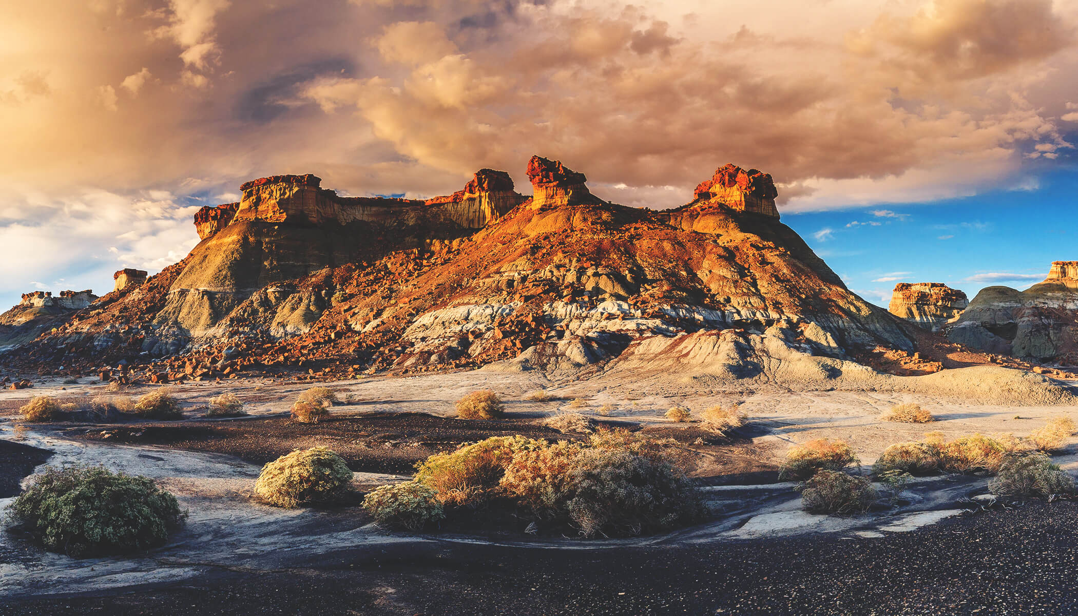 A majestic butte surrounded by a desert landscape at dusk