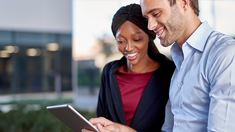 Two people looking at a tablet together and smiling 