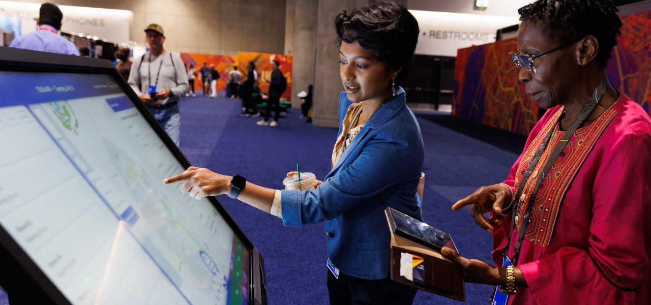 Two event attendees interact with a large touch screen in the Expo