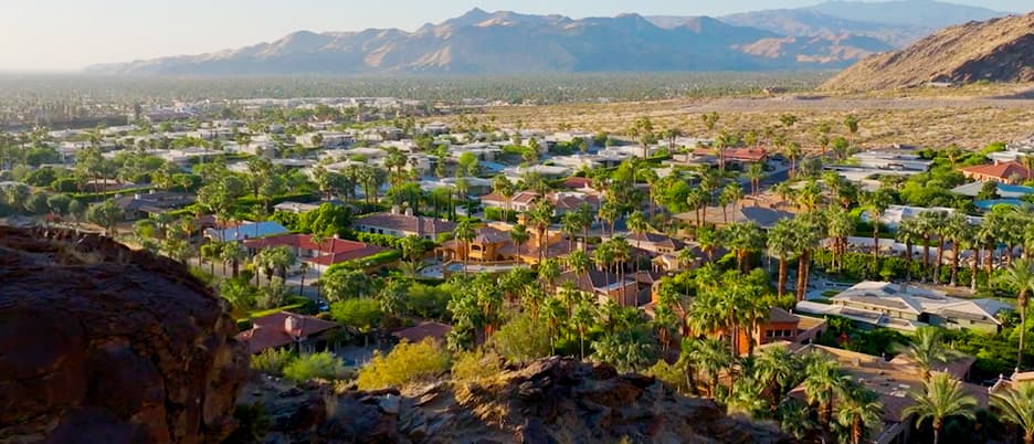 Aerial view over a neighborhood in Palm Springs, CA, palm trees and mountains in the background