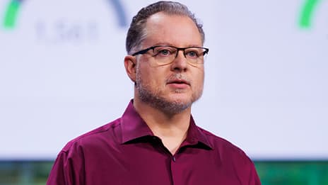 Presenter wearing a maroon polo shirt and glasses