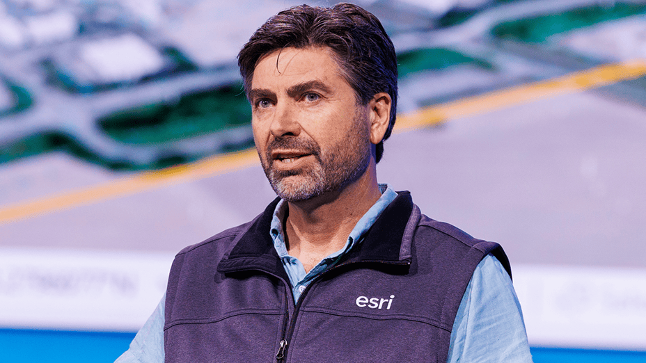 Portrait of a presenter with trimmed facial hair wearing an Esri vest