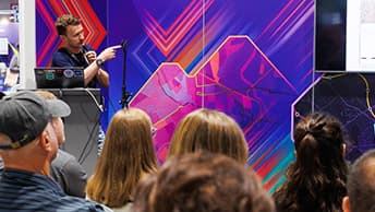 Presenter points to the right during a demonstration, audience in the foreground