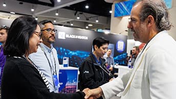 Two people shaking hands at a busy trade show