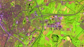 Satellite image of a city shaded in purple and fluorescent green with several intersecting freeways