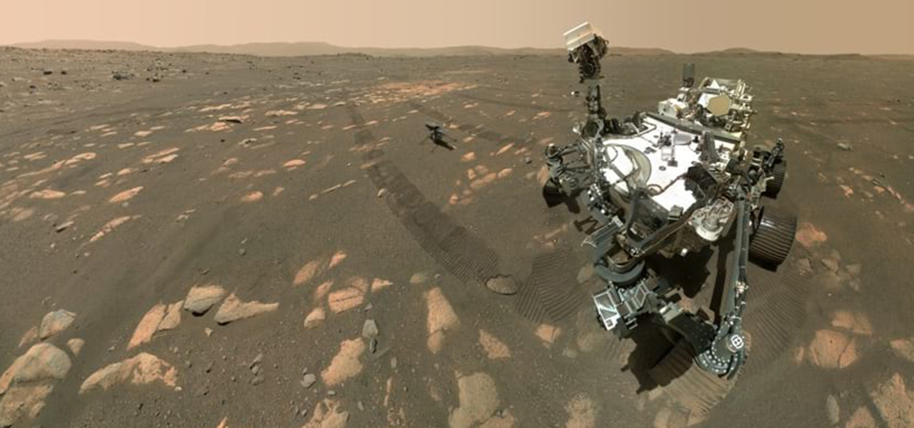 A rover resting alone on the gray and reddish surface of Mars under a dull pink sky