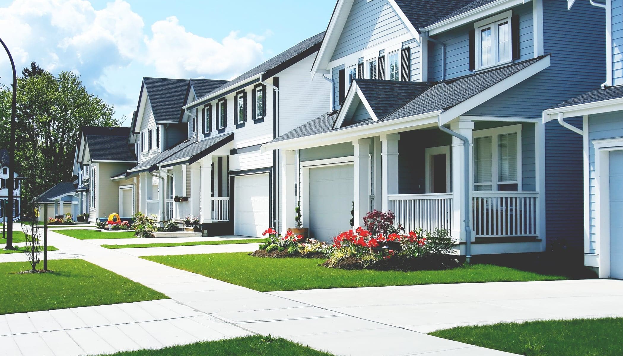 A row of tidy new blue-and-white houses with bright green lawns