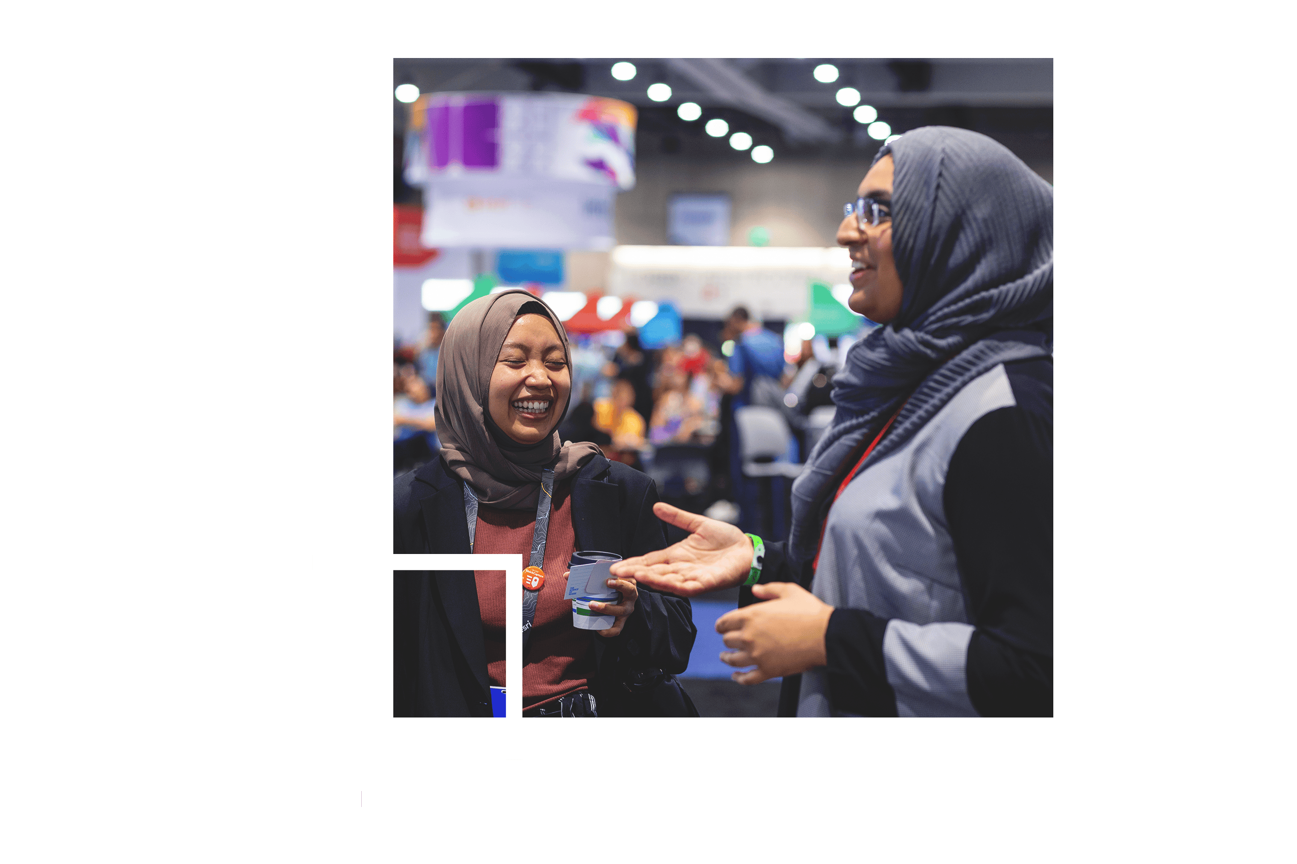 a small image of two people wearing conference lanyards and headscarves laughing together in a crowded exhibit hall, overlaid on a soft-focus image of a conference hall wall painted in a blue and pink abstract pattern