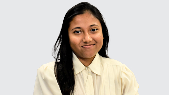 Trina Das smiling and wearing a cream collared blouse in front of a white background