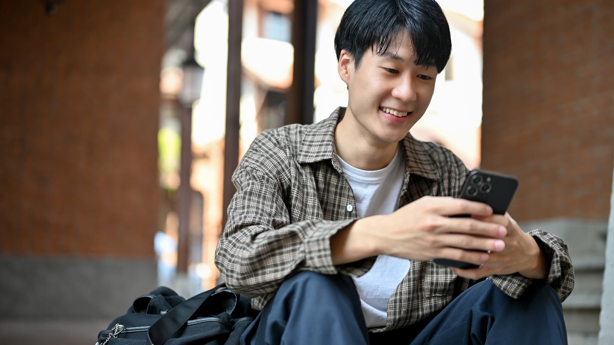 A casually-dressed person smiling at his mobile phone in a softly lit home environment