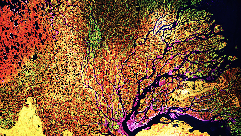 Imagens de satélite de sensoriamento remoto mostram um sistema fluvial cercado por uma paisagem colorida em vermelho, marrom, verde, amarelo e rosa