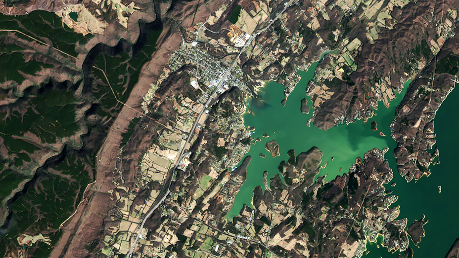 A coastal inlet winds past mountains to reach a densely populated area and nearby farmlands