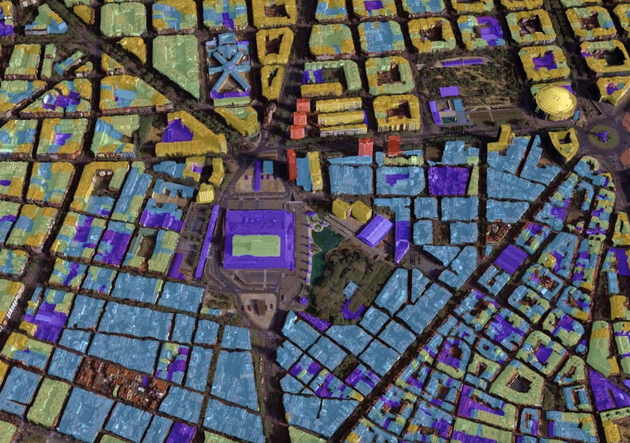 Vista aérea de edifícios 3D com sombreamento de cores amarelo, azul, verde e roxo, mostrando também estradas e espaços verdes abertos
