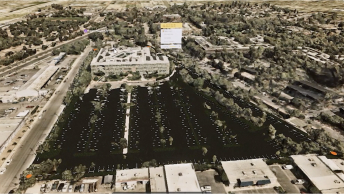 Shot of an XR experience showing the mesh layers of a building and large parking lot, surrounded by other buildings and trees