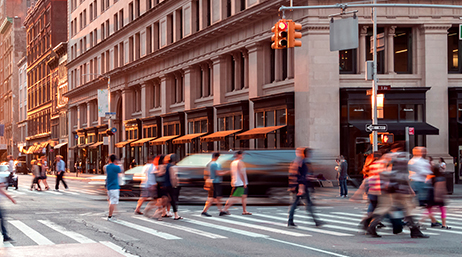 A city intersection at golden hour, with people crossing the street in slow exposure  