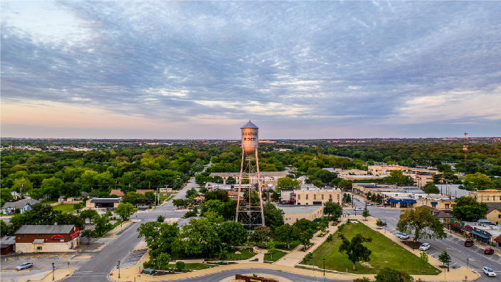 A water tower stands over a town and vast, flat land stretches beyond under a dusk sky 