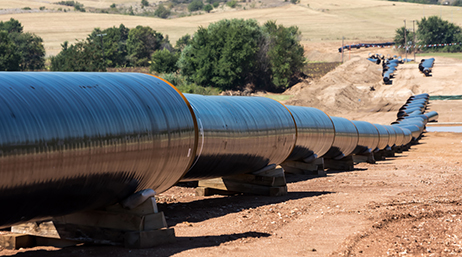 An aboveground utility pipeline snaking down a dirt slope