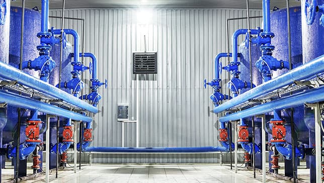 A large room with many blue pipes and red valves