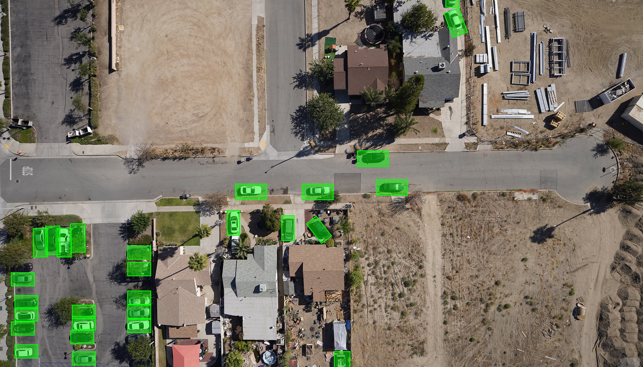 Aerial view of residential neighborhood, where AI has highlighted cars with green boxes