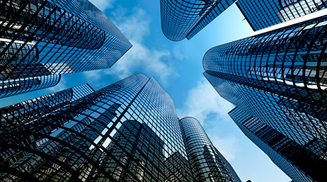 View from below of tall glass skyscraper buildings against the blue sky