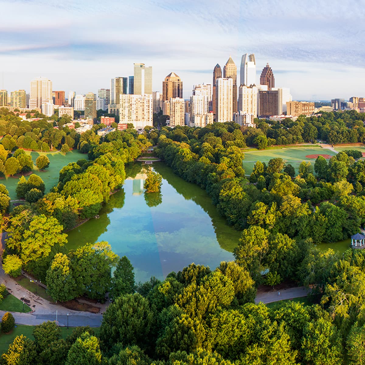 An expansive urban greenspace filled with trees, trails, and parks, with a dense cityscape in the background