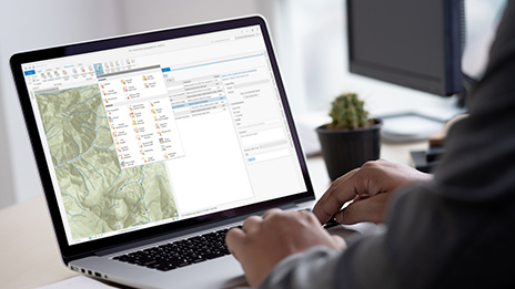 Mains travaillant sur un ordinateur portable qui affiche une carte et des données représentant des vérifications Data Reviewer dans ArcGIS Pro 