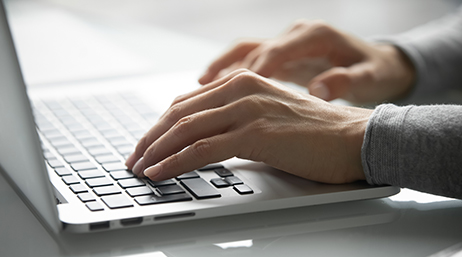 A pair of hands typing on a laptop computer at a desk