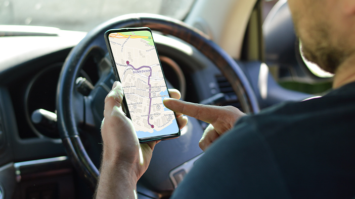 Persona en un coche mirando las indicaciones de la ruta en un dispositivo móvil 