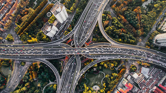 Veicoli che seguono indicazioni stradali su autostrade trafficate sopra parchi ed edifici vicini