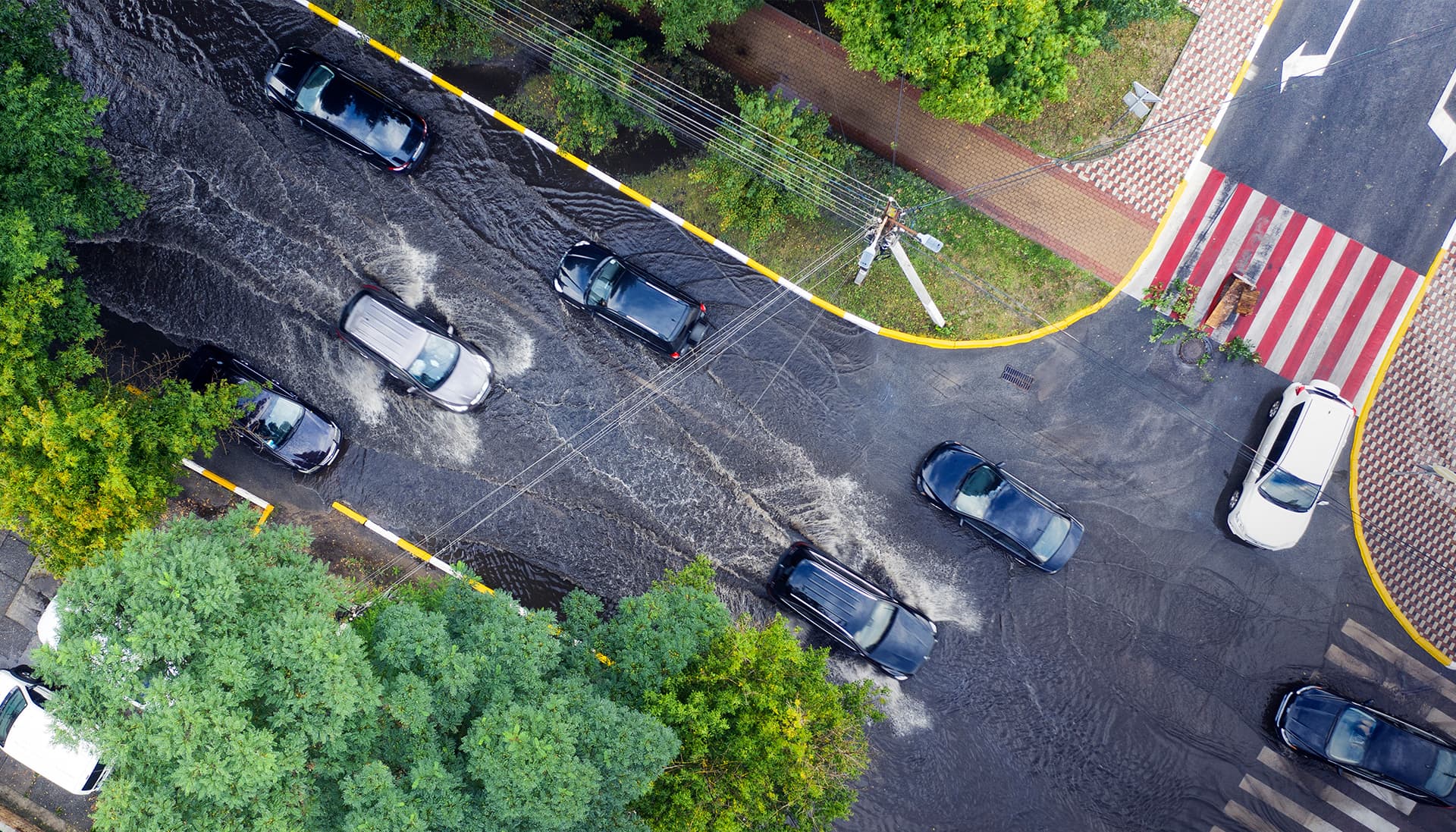 Aerial photograph of cars driving through flooded streets