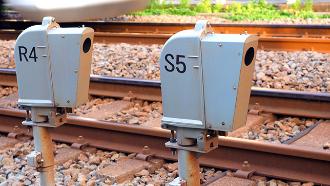 Dwie małe skrzynki czujników, oznaczone odpowiednio R4 i S5, obok toru kolejowego